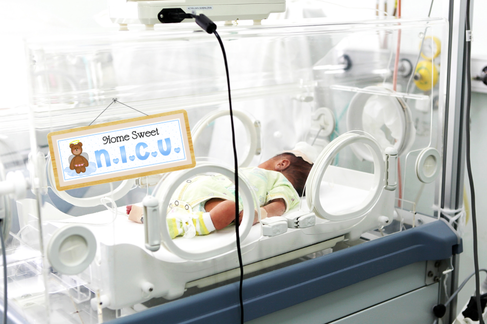 NICU baby in hospital isolette with printable word sheet concept for documenting preemie journey and memory book creation